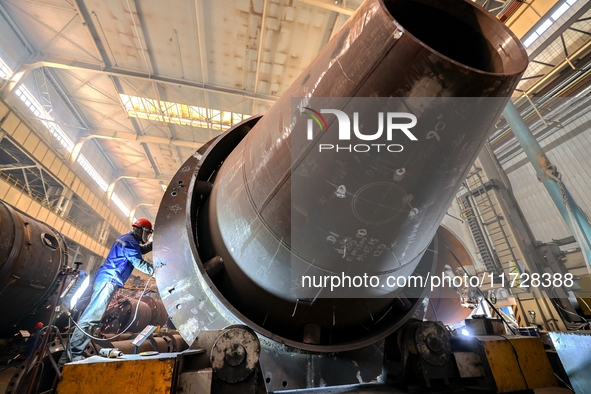 An employee works on a large pressure vessel customized by an oil refinery at the production workshop of Qingdao Lanshi Heavy Machinery Equi...