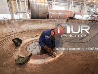 An employee works on a large pressure vessel customized by an oil refinery at the production workshop of Qingdao Lanshi Heavy Machinery Equi...