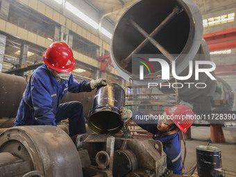 An employee works on a large pressure vessel customized by an oil refinery at the production workshop of Qingdao Lanshi Heavy Machinery Equi...