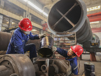 An employee works on a large pressure vessel customized by an oil refinery at the production workshop of Qingdao Lanshi Heavy Machinery Equi...