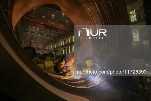 An employee works on a large pressure vessel customized by an oil refinery at the production workshop of Qingdao Lanshi Heavy Machinery Equi...