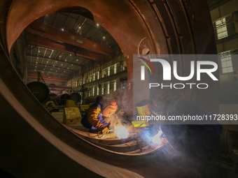 An employee works on a large pressure vessel customized by an oil refinery at the production workshop of Qingdao Lanshi Heavy Machinery Equi...