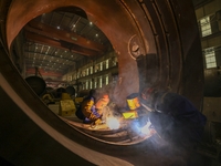 An employee works on a large pressure vessel customized by an oil refinery at the production workshop of Qingdao Lanshi Heavy Machinery Equi...