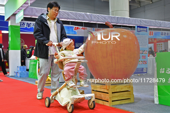 A visitor brings a child to the 2024 Yantai International Food (Prepared Dishes) Industry Expo in Yantai, China, on November 1, 2024. 