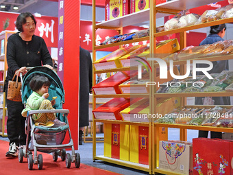 A visitor brings a child to the 2024 Yantai International Food (Prepared Dishes) Industry Expo in Yantai, China, on November 1, 2024. (