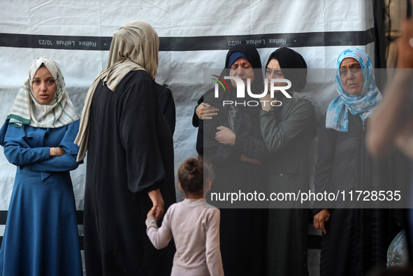 Palestinian women react beside the bodies of victims from an Israeli airstrike that targets a house in the Nuseirat refugee camp in central...