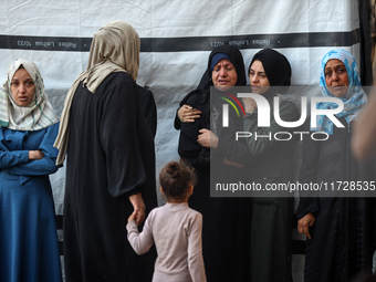 Palestinian women react beside the bodies of victims from an Israeli airstrike that targets a house in the Nuseirat refugee camp in central...