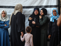 Palestinian women react beside the bodies of victims from an Israeli airstrike that targets a house in the Nuseirat refugee camp in central...