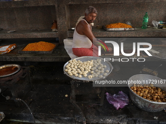 A worker prepares offerings before distributing them to devotees after worship as part of the celebration of the Hindu festival of Kali Puja...