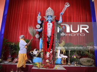 A Hindu priest, C, performs rituals while he prays in front of an idol of the Hindu goddess Kali inside a ''pandal,'' a decorated temporary...