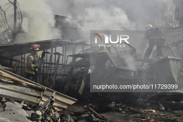 Firefighters extinguish the blaze at the site of overnight Israeli airstrikes that target the neighborhood of Kafaat in Beirut's southern su...