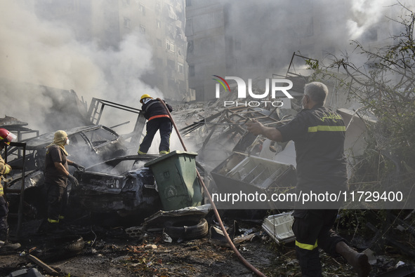 Firefighters extinguish the blaze at the site of overnight Israeli airstrikes that target the neighborhood of Kafaat in Beirut's southern su...