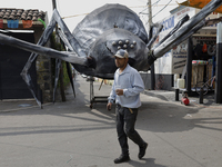 A resident of Santiago Zapotitlan, Tlahuac, walks in front of a monumental spider in Mexico City, Mexico, on November 1, 2024, heading to th...