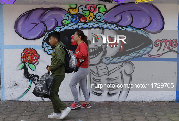 Residents of Santiago Zapotitlan, Tlahuac, walk in front of a mural in Mexico City, Mexico, on November 1, 2024, as they head to the communi...