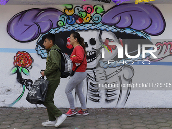 Residents of Santiago Zapotitlan, Tlahuac, walk in front of a mural in Mexico City, Mexico, on November 1, 2024, as they head to the communi...