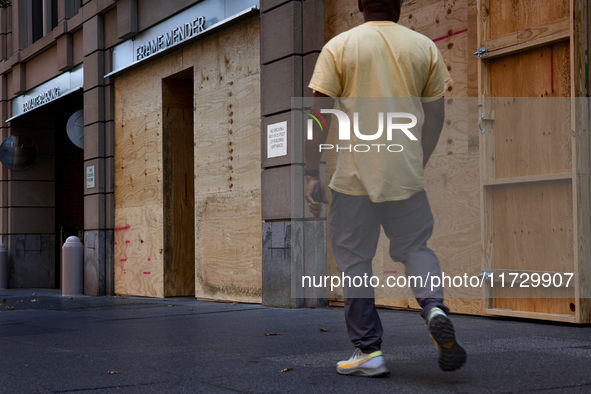 A person walks past boarded up storefronts near the White House in Washington, D.C. on November 1, 2024 as local busineses prepare for possi...