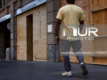 A person walks past boarded up storefronts near the White House in Washington, D.C. on November 1, 2024 as local busineses prepare for possi...