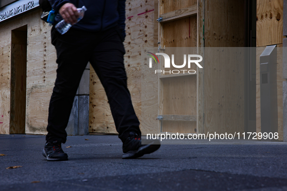 A person walks past boarded up storefronts near the White House in Washington, D.C. on November 1, 2024 as local busineses prepare for possi...