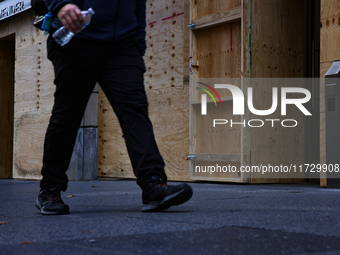 A person walks past boarded up storefronts near the White House in Washington, D.C. on November 1, 2024 as local busineses prepare for possi...