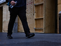 A person walks past boarded up storefronts near the White House in Washington, D.C. on November 1, 2024 as local busineses prepare for possi...