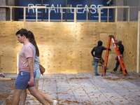 People walk past boarded up storefronts near the White House in Washington, D.C. on November 1, 2024 as local busineses prepare for possible...