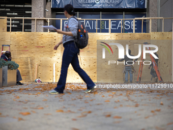 A person walks past boarded up storefronts near the White House in Washington, D.C. on November 1, 2024 as local busineses prepare for possi...