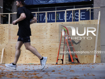 A person jogs past boarded up storefronts near the White House in Washington, D.C. on November 1, 2024 as local busineses prepare for possib...