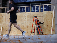 A person jogs past boarded up storefronts near the White House in Washington, D.C. on November 1, 2024 as local busineses prepare for possib...