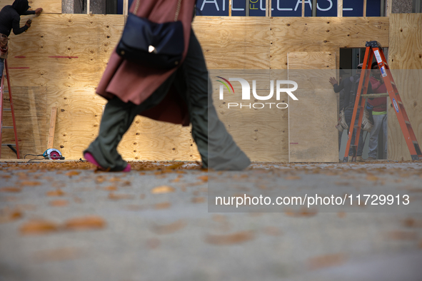 A person walks past boarded up storefronts near the White House in Washington, D.C. on November 1, 2024 as local busineses prepare for possi...