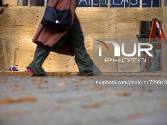 A person walks past boarded up storefronts near the White House in Washington, D.C. on November 1, 2024 as local busineses prepare for possi...