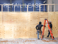 Workers cover storefront entrances with plywood near the White House in Washington, D.C. on November 1, 2024 in preparation for possible civ...