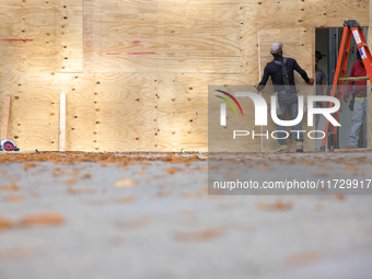 Workers cover storefront entrances with plywood near the White House in Washington, D.C. on November 1, 2024 in preparation for possible civ...