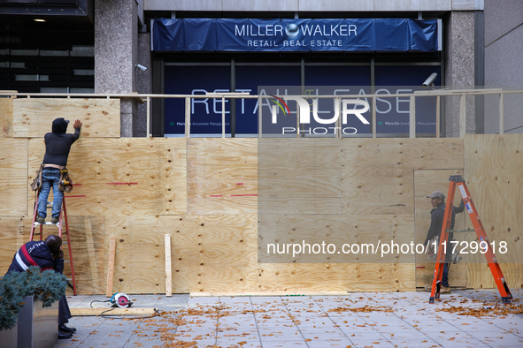 Workers cover storefront entrances with plywood near the White House in Washington, D.C. on November 1, 2024 in preparation for possible civ...