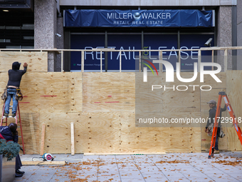 Workers cover storefront entrances with plywood near the White House in Washington, D.C. on November 1, 2024 in preparation for possible civ...