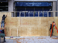 Workers cover storefront entrances with plywood near the White House in Washington, D.C. on November 1, 2024 in preparation for possible civ...