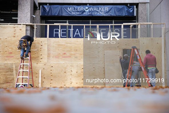 Workers cover storefront entrances with plywood near the White House in Washington, D.C. on November 1, 2024 in preparation for possible civ...