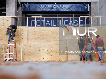 Workers cover storefront entrances with plywood near the White House in Washington, D.C. on November 1, 2024 in preparation for possible civ...