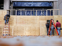 Workers cover storefront entrances with plywood near the White House in Washington, D.C. on November 1, 2024 in preparation for possible civ...