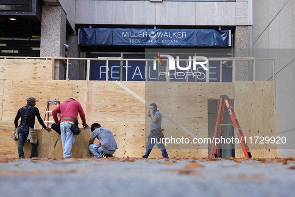 Workers cover storefront entrances with plywood near the White House in Washington, D.C. on November 1, 2024 in preparation for possible civ...