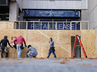 Workers cover storefront entrances with plywood near the White House in Washington, D.C. on November 1, 2024 in preparation for possible civ...