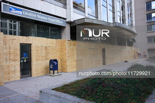 Workers cover storefront entrances with plywood near the White House in Washington, D.C. on November 1, 2024 in preparation for possible civ...