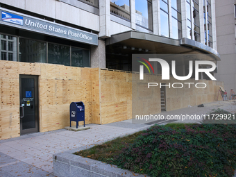 Workers cover storefront entrances with plywood near the White House in Washington, D.C. on November 1, 2024 in preparation for possible civ...