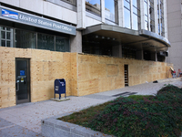 Workers cover storefront entrances with plywood near the White House in Washington, D.C. on November 1, 2024 in preparation for possible civ...