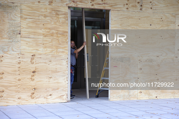 Workers cover storefront entrances with plywood near the White House in Washington, D.C. on November 1, 2024 in preparation for possible civ...