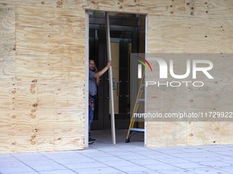 Workers cover storefront entrances with plywood near the White House in Washington, D.C. on November 1, 2024 in preparation for possible civ...