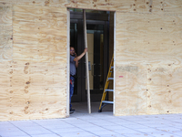 Workers cover storefront entrances with plywood near the White House in Washington, D.C. on November 1, 2024 in preparation for possible civ...