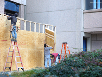 Workers cover storefront entrances with plywood near the White House in Washington, D.C. on November 1, 2024 in preparation for possible civ...