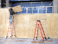 Workers cover storefront entrances with plywood near the White House in Washington, D.C. on November 1, 2024 in preparation for possible civ...