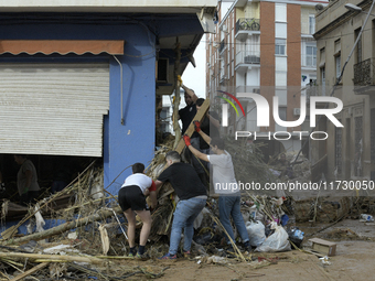 People clear mud and possessions from their homes after flash flooding in Paiporta, Spain, on November 1, 2024. (