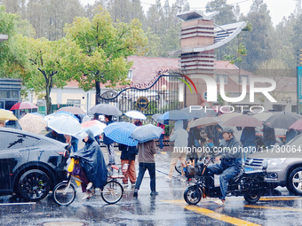 Parents hold umbrellas to pick up their children from school after Typhoon Kong-Rey brings strong winds and heavy rain in Shanghai, China, o...